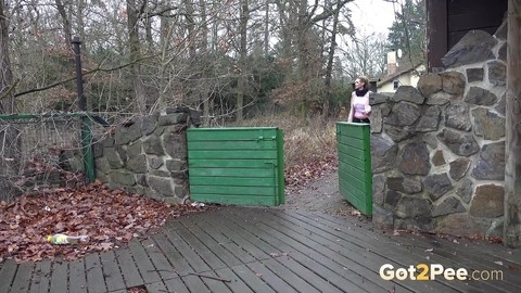 White girl Cynthia Vellons takes a piss on a deck behind a stone structure | Фото 1