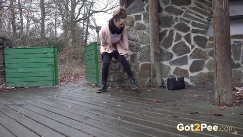 White girl Cynthia Vellons takes a piss on a deck behind a stone structure | Фото 3