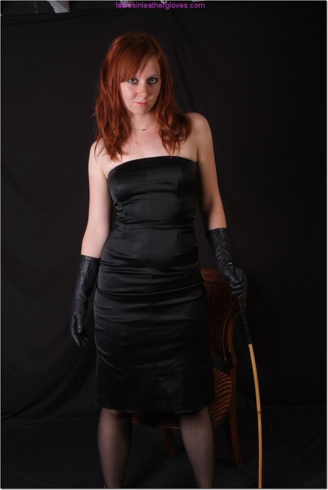 Sexy redhead flexes a cane before touching her tight slit with leather gloves