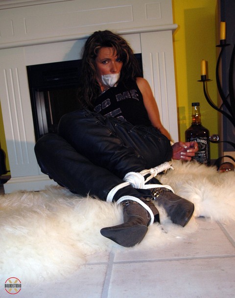 Solo girl has her wrists tied to her legs in leather pants while gagged | Фото 16