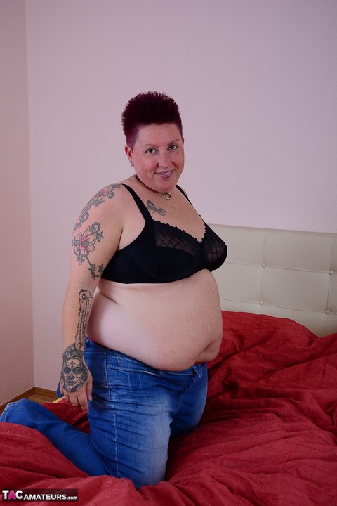 Overweight amateur Tattoo Girl lets a breast escape from her bra on a bed