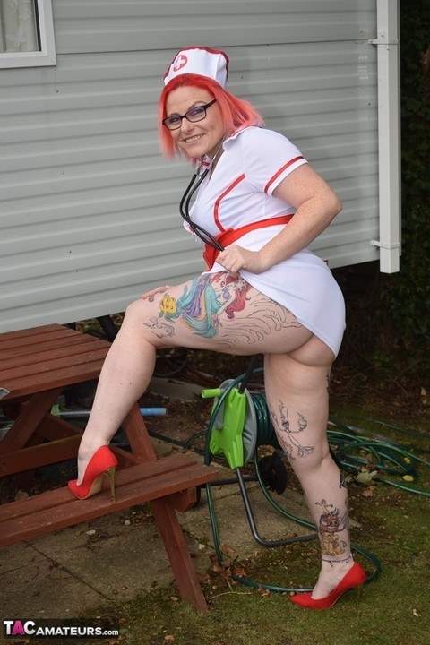 Thick redhead removes leather attire to pose nude before donning nurse garb | Фото 20