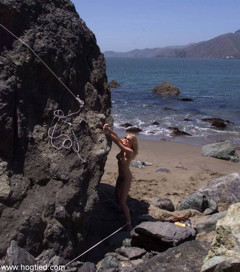 Nude mature slave Sadie Belle gets tied to a huge rock on the beach | Фото 11