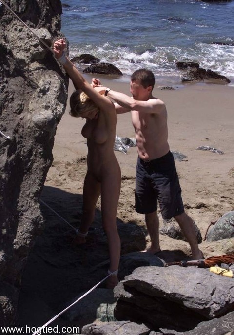 Nude mature slave Sadie Belle gets tied to a huge rock on the beach | Фото 12