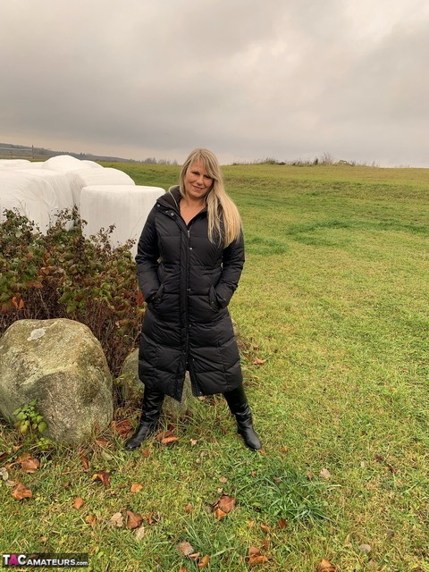 Older blonde Sweet Susi exposes herself in a field while wearing a winter coat