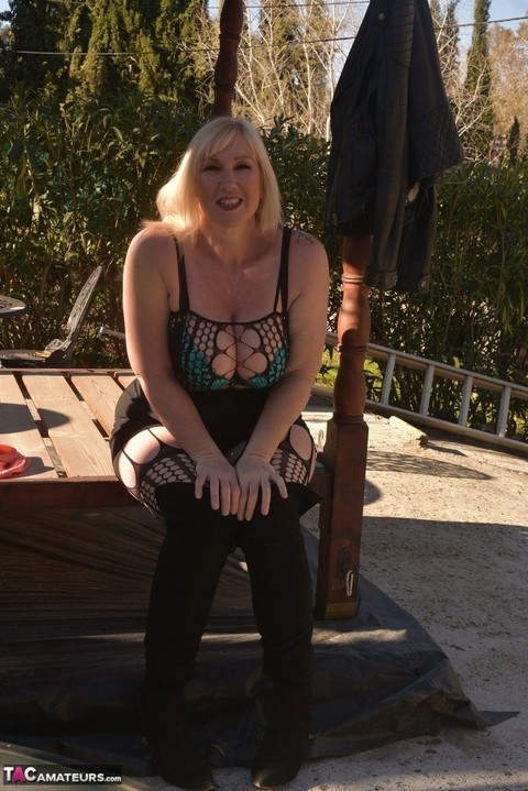 Overweight blonde Melody uncovers her brassiere on a patio in OTK boots | Фото 12