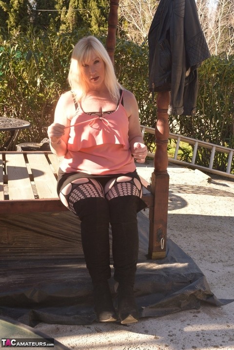 Overweight blonde Melody uncovers her brassiere on a patio in OTK boots | Фото 8