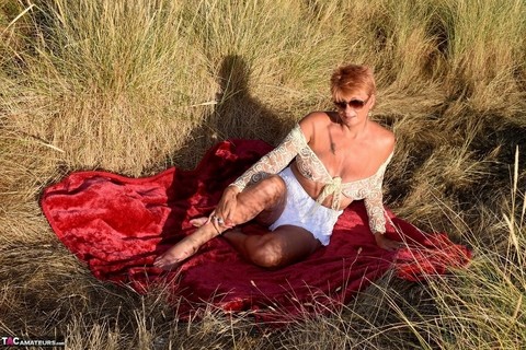 Mature redhead Dimonty exposes her sagging tits on a bench down by the sea | Фото 8