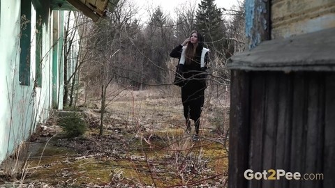 Solo girl pulls down black hose before squatting to pee beside a building | Фото 1