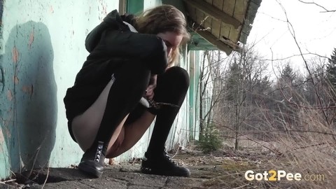 Solo girl pulls down black hose before squatting to pee beside a building | Фото 10