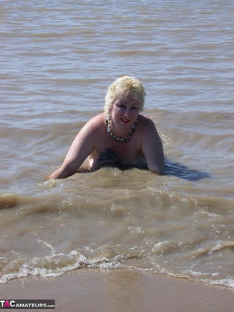 Older blonde amateur Mary Bitch takes a pee before going topless in the ocean