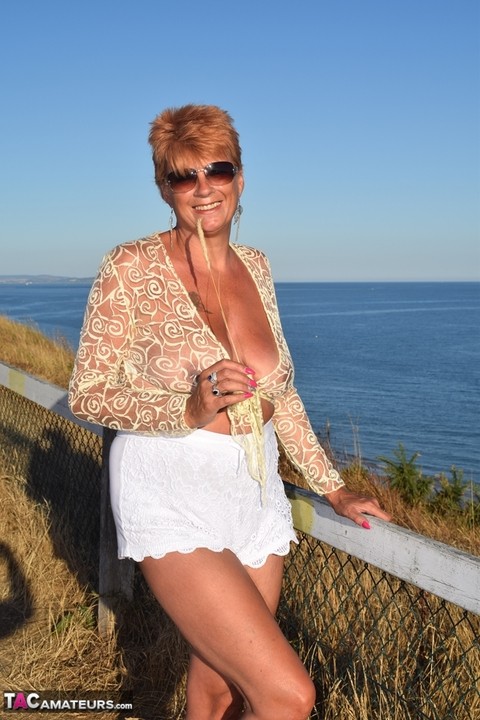 Mature woman with red hair lets her saggy tits free overlooking the ocean | Фото 7