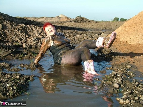 Mature redhead Valgasmic Exposed covers her fat body in mud | Фото 1