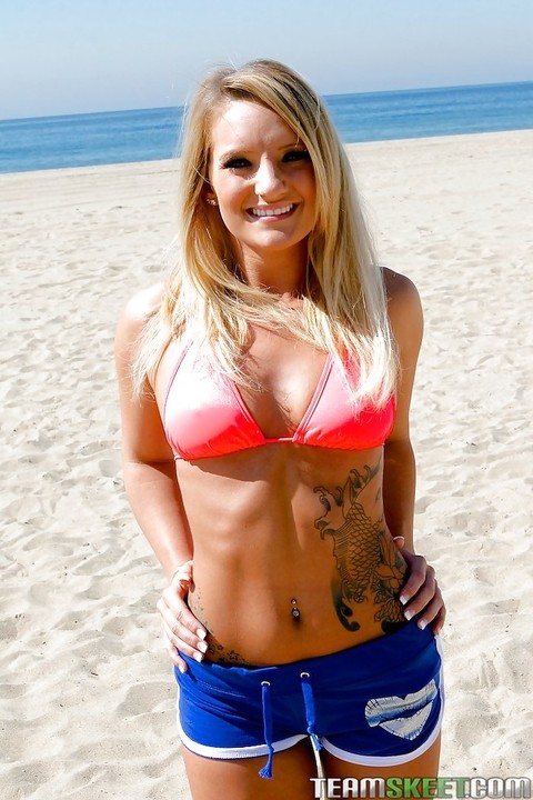 Smiley blonde sweetie with tattoos revealing her tits on the sand beach | Фото 4