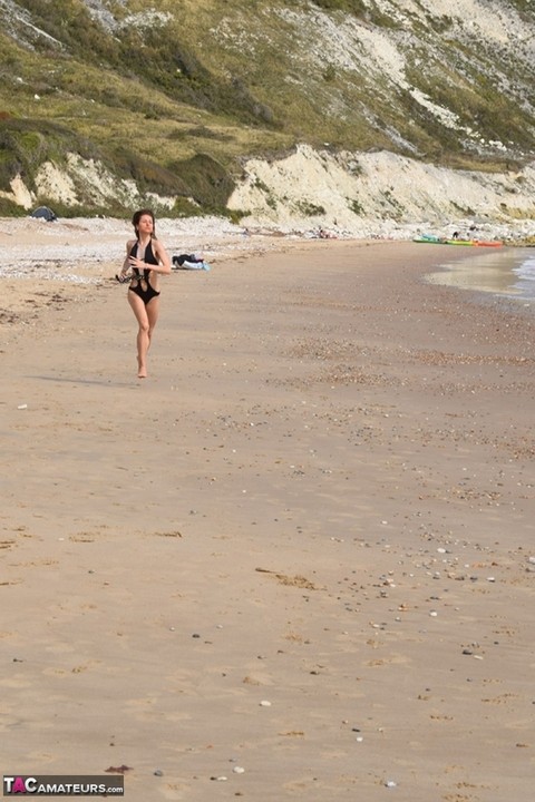 Slender female models a bathing suit while at a deserted beach | Фото 4