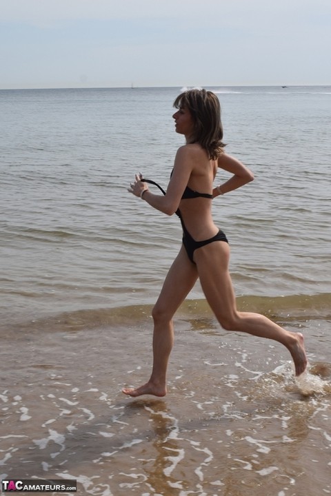 Slender female models a bathing suit while at a deserted beach | Фото 7