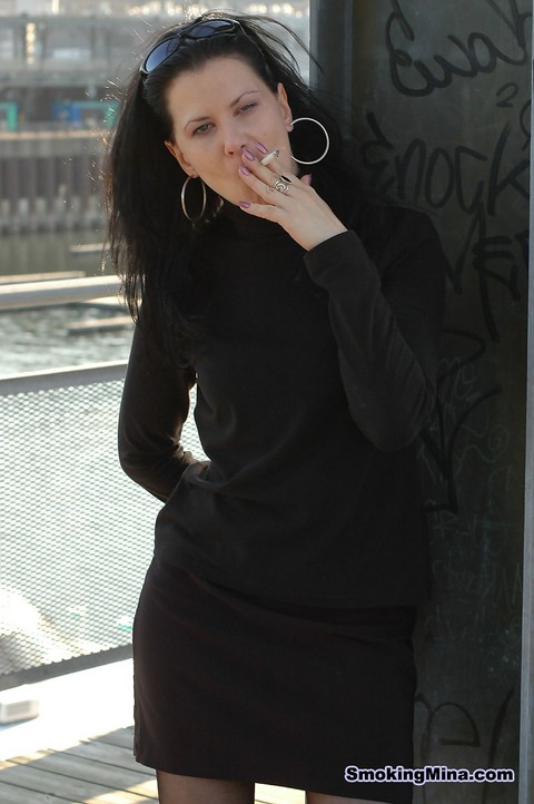 Fully clothed brunette lights up a cigarette with her sunglasses atop her head | Фото 11