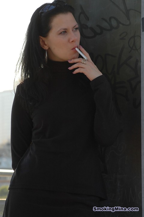 Fully clothed brunette lights up a cigarette with her sunglasses atop her head | Фото 2