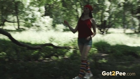 Young blonde Larisa takes a pee behind a tree in multi-coloured knee socks