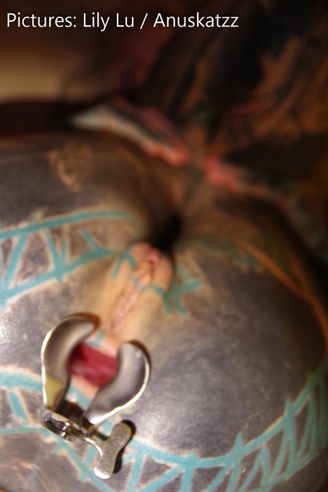 Heavily tattooed girl has her asshole stretched open while somewhat restrained