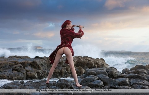 Busty redhead Ariel looks through a spyglass while naked at the ocean | Фото 2