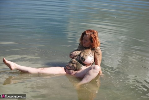 Redheaded amateur Misha covers her big tits in mud while in shallow water | Фото 13