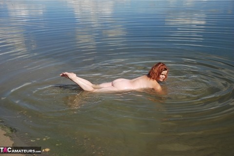 Redheaded amateur Misha covers her big tits in mud while in shallow water | Фото 15