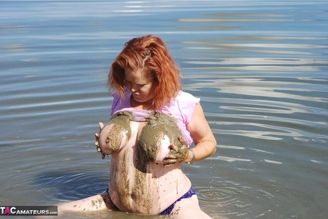 Redheaded amateur Misha covers her big tits in mud while in shallow water | Фото 5