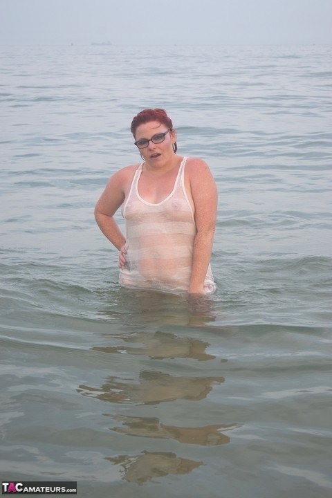 Tattooed redhead wades into the ocean before exposing herself